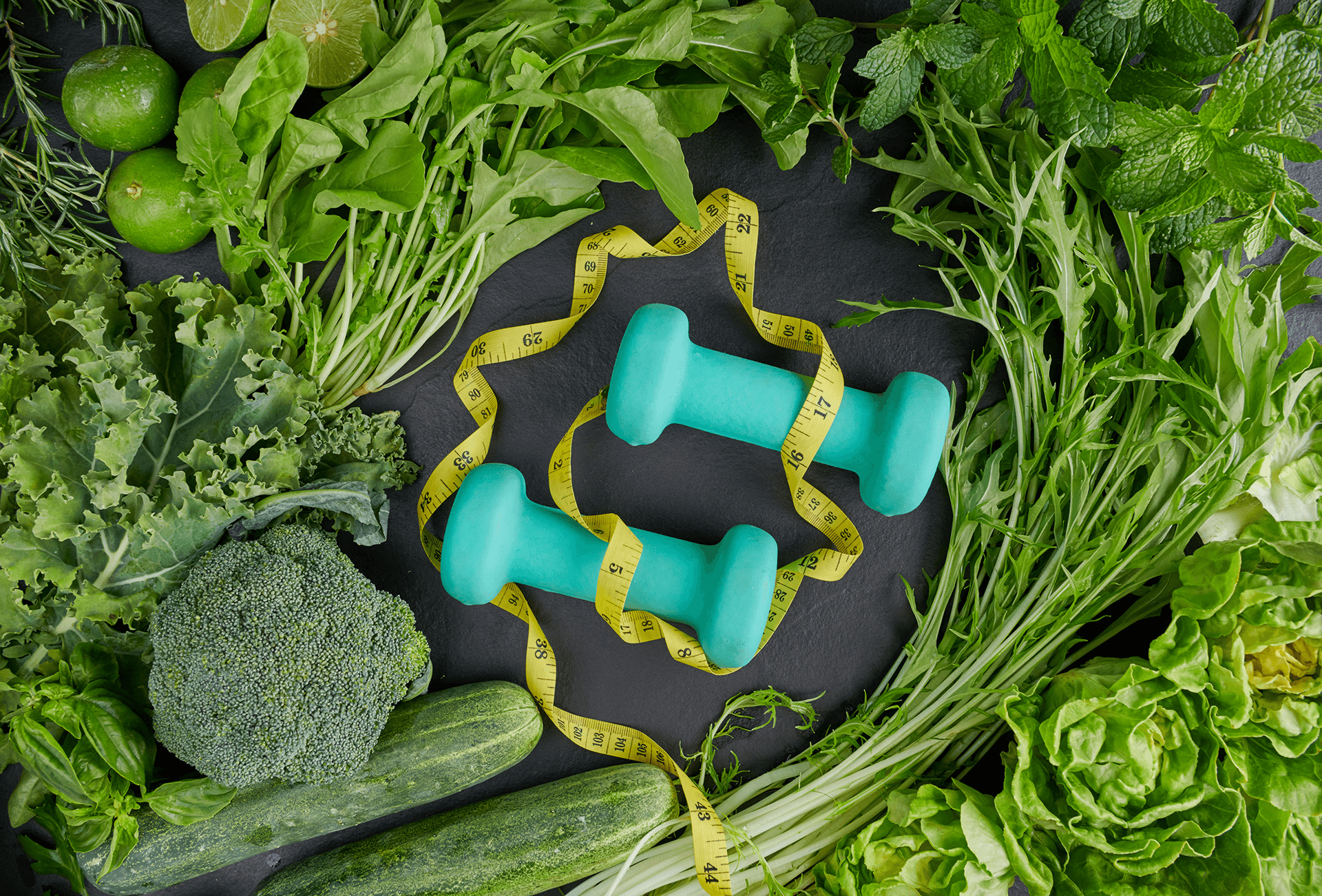 Fresh green vegetables, dumbbells, and measuring tape for healthy lifestyle