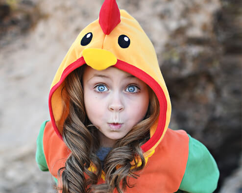 Child wearing colorful chicken costume hoodie outdoors