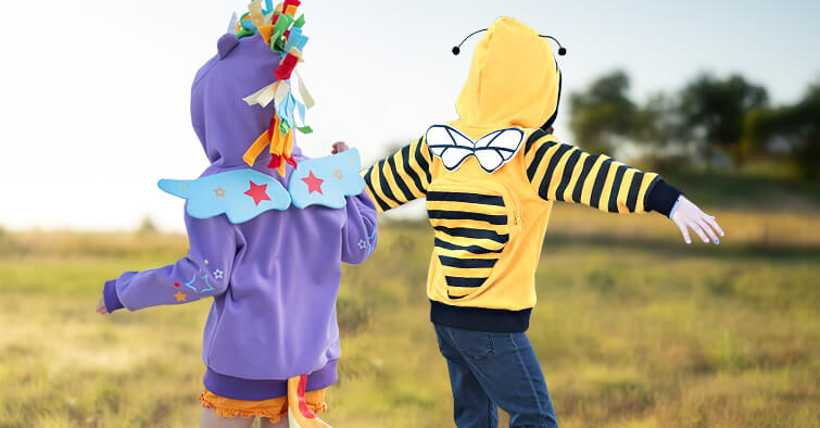 Two children wearing colorful animal costume hoodies playing outdoors