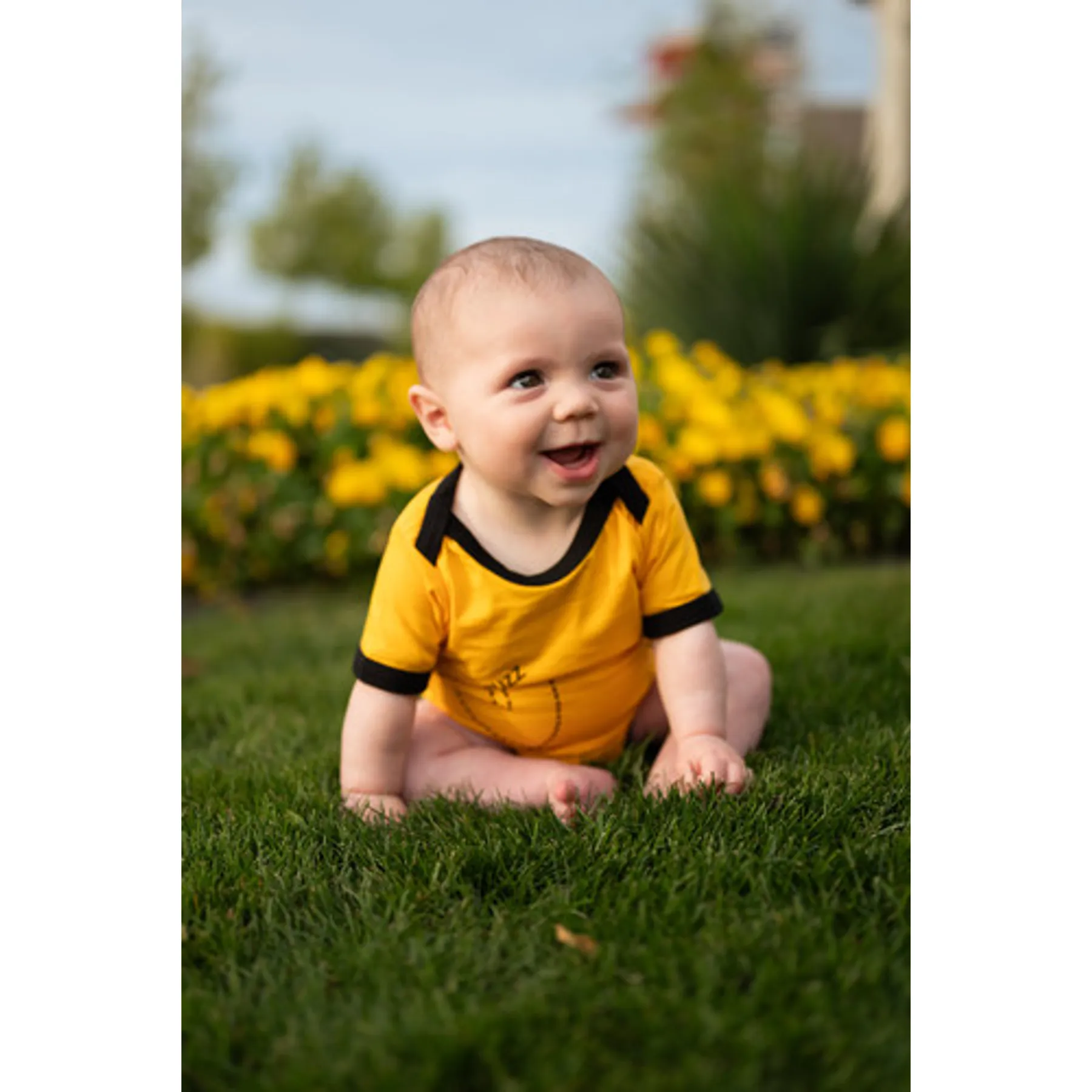 Baby wearing Buzz the Bee bodysuit in grass