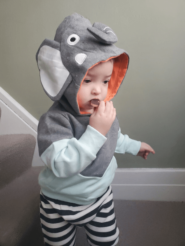 Toddler wearing gray elephant costume hoodie with striped pants