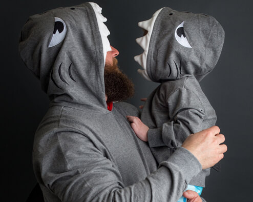 Adult and child wearing matching gray dinosaur hooded sweatshirts