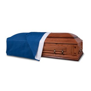A closed wooden casket partailly draped with a blue quilted casket blanket.